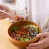 Person eating a colorful anti-inflammatory salad bowl with beans, greens, and chopped vegetables