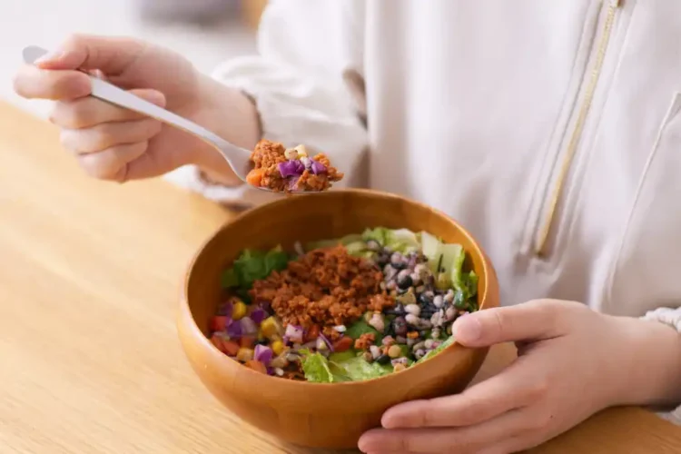 Person eating a colorful anti-inflammatory salad bowl with beans, greens, and chopped vegetables