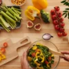 Top-down view of a beginner preparing a colorful plant-based anti-inflammatory salad with fresh vegetables and whole ingredients on a wooden surface.