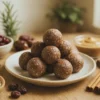 Anti-inflammatory energy balls on a ceramic plate with oats, dates, tart cherries, almond butter, dark chocolate, and cinnamon